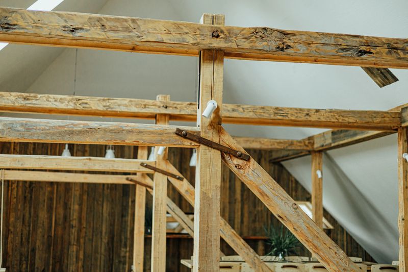 Close-up of exposed rustic wooden beams forming a sturdy attic framework, highlighting natural textures, craftsmanship, and minimalist Nordic interior charm