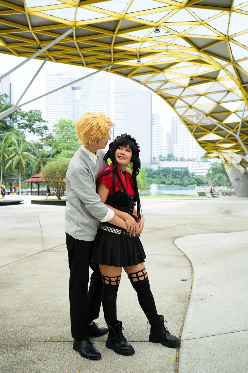 Two cosplayers are hugging each other under a modern architectural structure