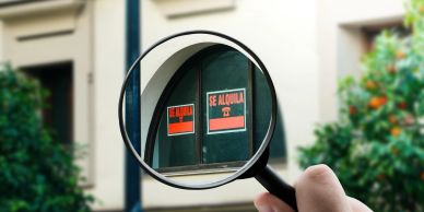 Magnifying glass focusing on a window with 'Se Alquila' signs.
