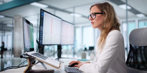 Woman working on a computer with multiple screens in a modern office.