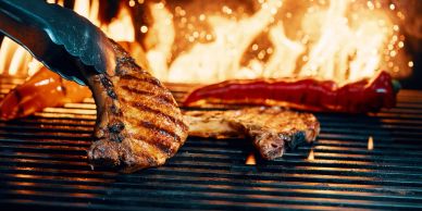 Grilled steaks cooking over an open flame.