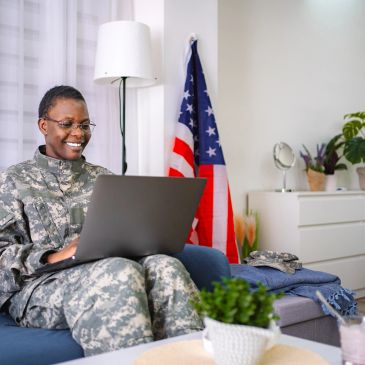 Smiling soldier using laptop at home.