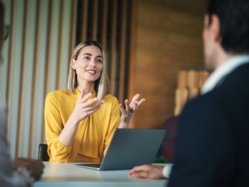 Woman in yellow speaking during a meeting.