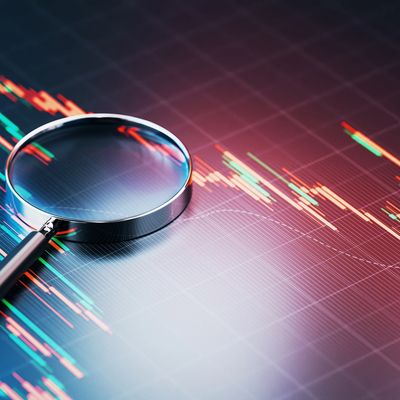 Magnifying glass over a digital stock market chart.