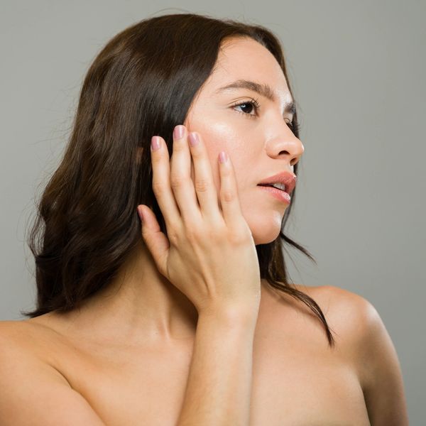 Woman touching her face, looking thoughtful.