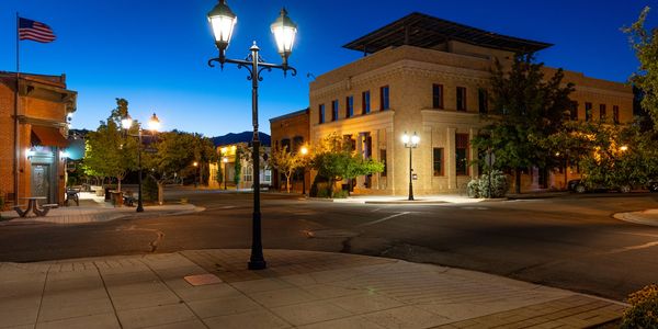 Quiet small-town street corner at dusk with vintage street lamps and American flag.