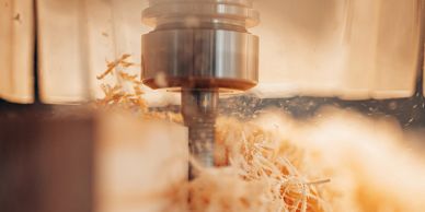 Close-up of a CNC machine cutting wood with shavings flying.