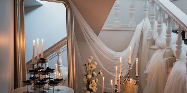 Elegant staircase decorated with candles, flowers, and fabric.