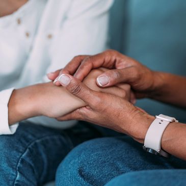 Two people holding hands in a comforting gesture.
