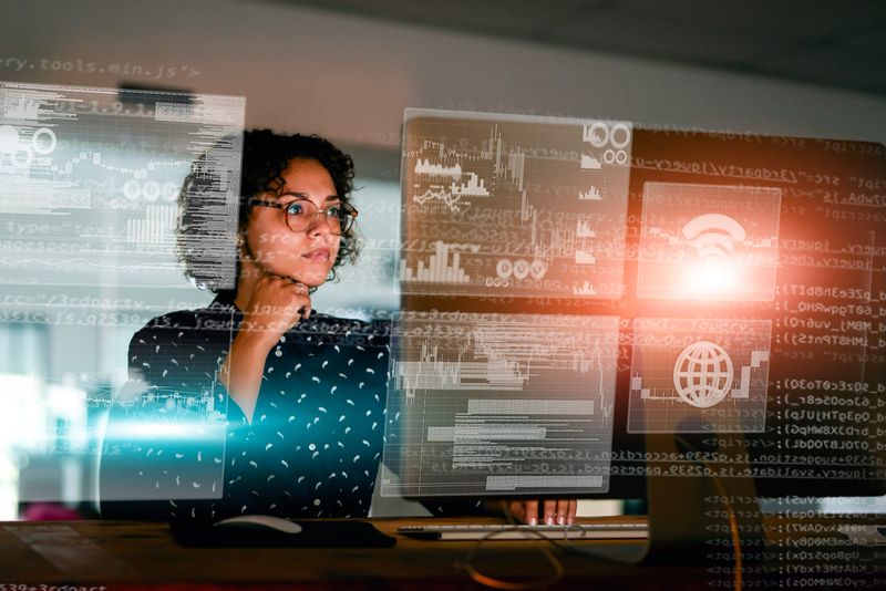 A professional studying advanced data and analytics on an interactive transparent display, showcasing technology and innovation in a modern workspace.