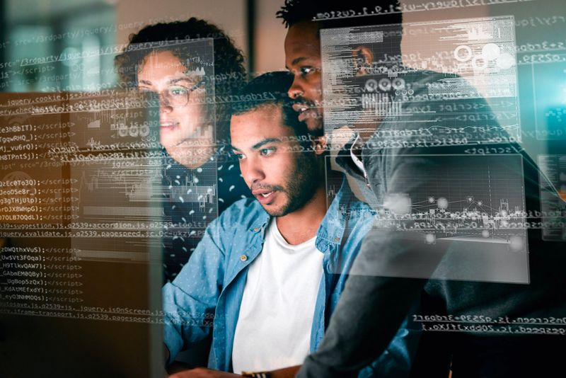 Three developers focused on coding and project collaboration, engaging with graphical interface overlays in a professional workspace. This image highlights teamwork, technology, and innovation in software development.