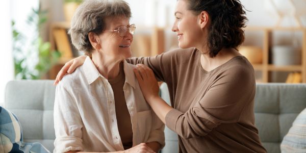 Young woman comforting elderly woman with a smile.