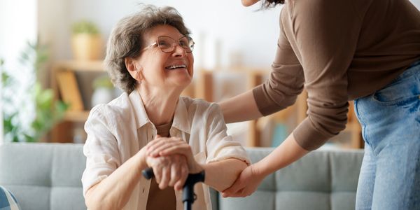 Elderly woman smiling while holding hands with caregiver.