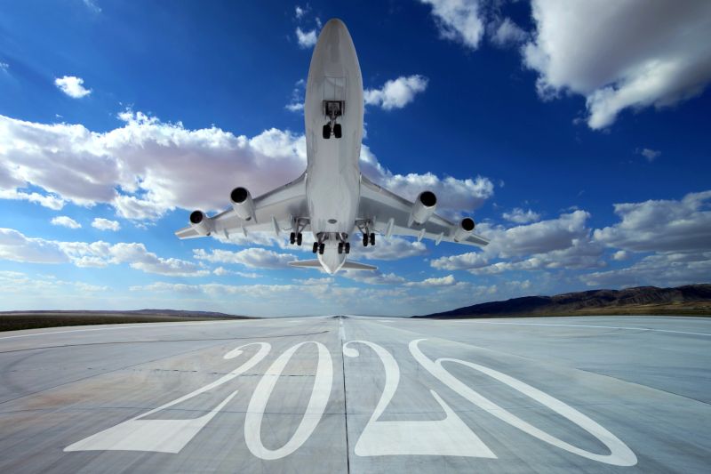 A jet airliner takes off into a dramatic blue sky from a runway printed with the number 2026, representing bold steps into the future.