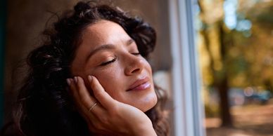 Woman peacefully resting her face on her hand with eyes closed.