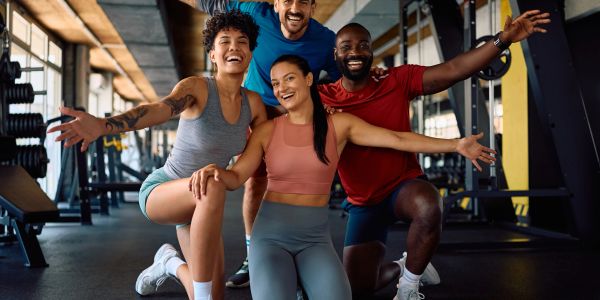 Four friends happily posing together in a gym workout session.
