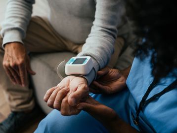 Healthcare worker checking patient's blood pressure.