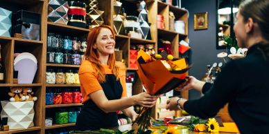 Florist hands a flower bouquet to a customer.