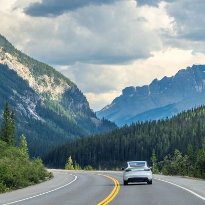 Car driving on mountain road with cloudy sky.