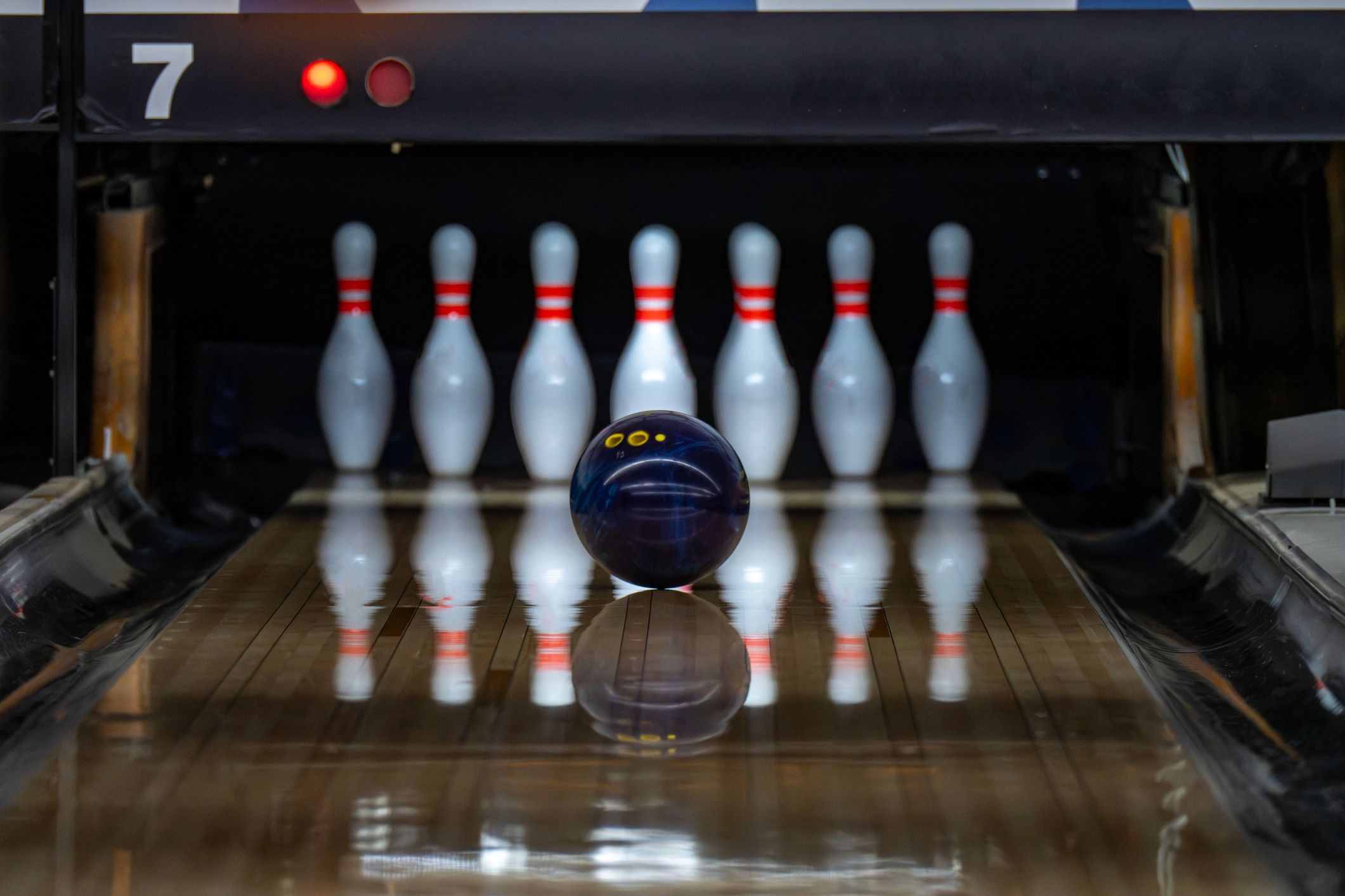 A bowling ball rolling towards pins down a lane.