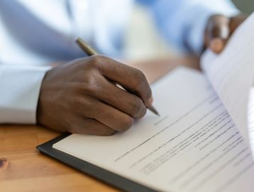 Close-up of a person signing an official document with a pen.
