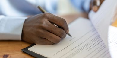 A person writing on a document with a pen.