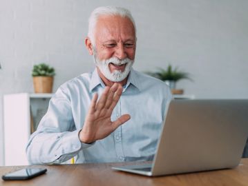 Smiling man receiving remote computer support through a video call on his laptop