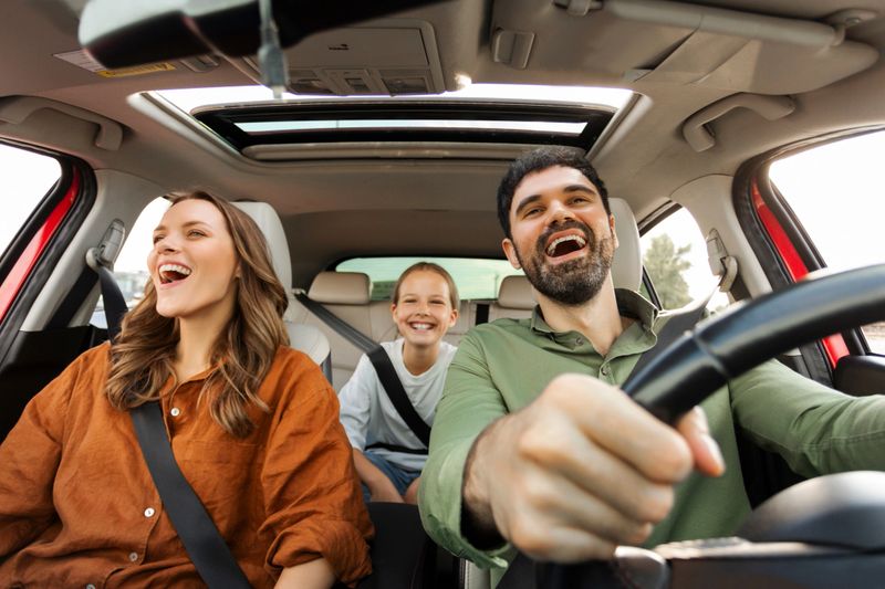 Joyful family riding car, having fun and chatting during road trip, parents and daughter traveling by auto. Transportation concept