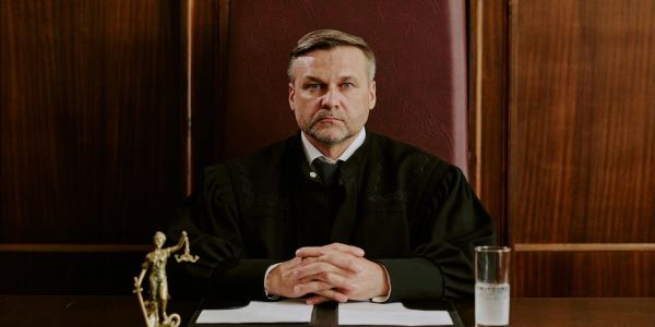 Serious male judge sitting at his bench in courtroom.