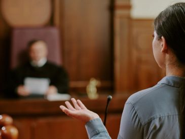 A woman testifying in court facing a judge.