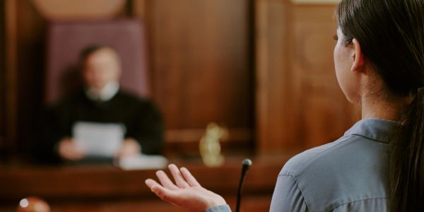 A woman testifying in court with a judge listening.