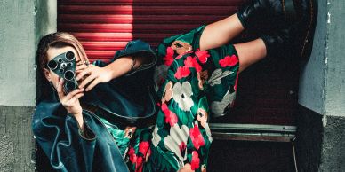 Woman taking photo with vintage camera in floral dress.
