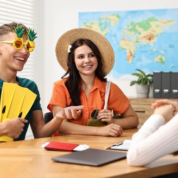 Couple discussing travel plans with agent, man in pineapple glasses.
