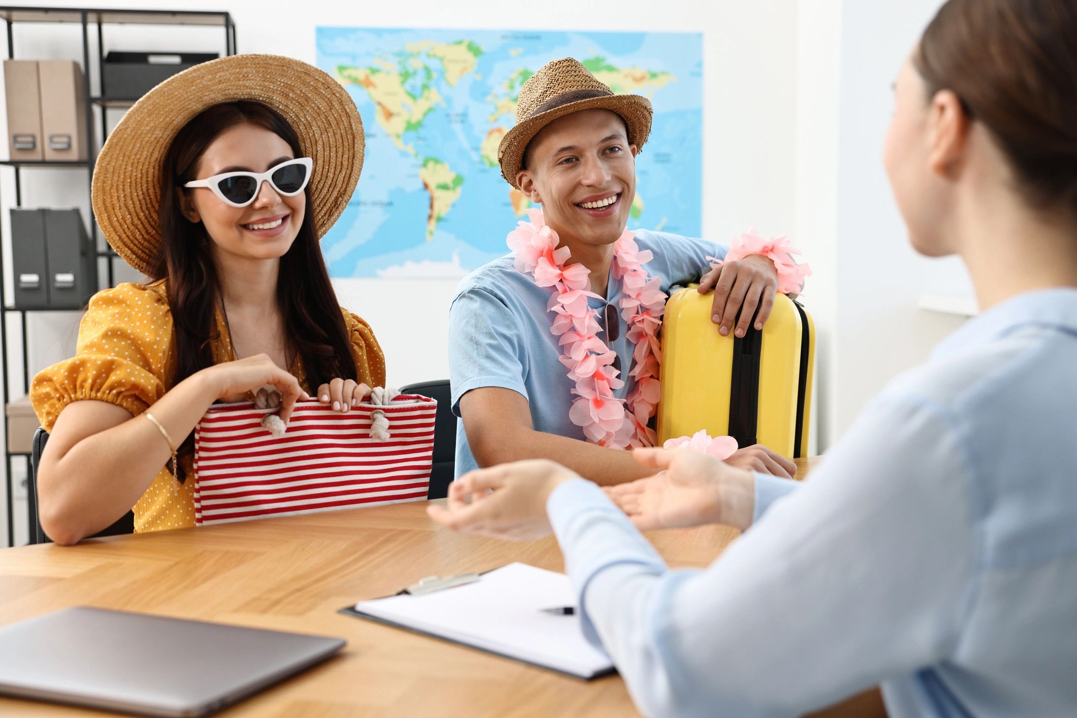 Couple in summer attire planning a trip with a travel agent.