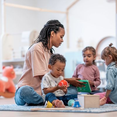 Woman reading to children while they play with toys.