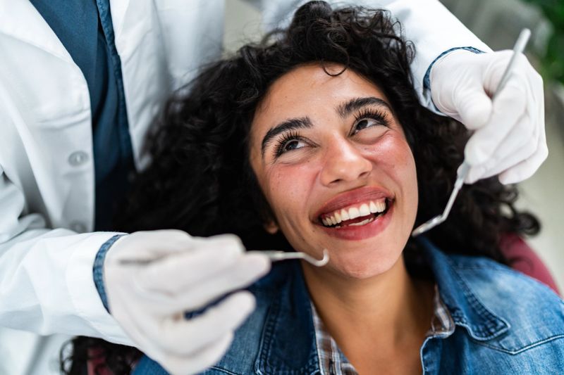 Dentist examining young patient woman teeth at dentist's office