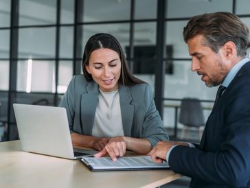 Colleagues reviewing documents on laptop