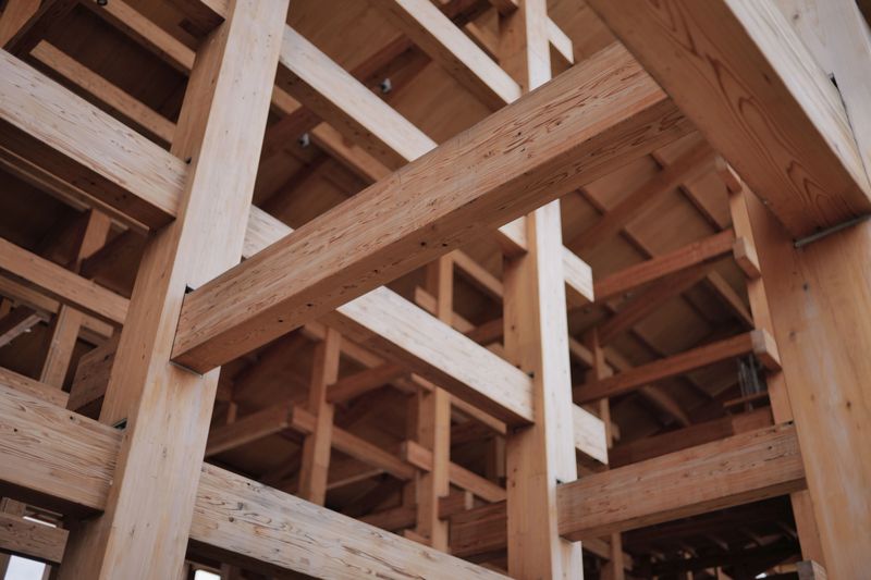 Vue rapprochée d'une structure architecturale en bois montrant des poutres et assemblages complexes.