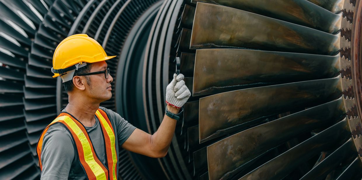 Technician inspecting large turbine blades with a magnifying glass.