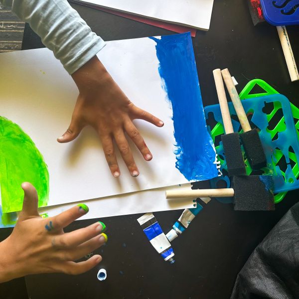 Child painting with blue and green colors.