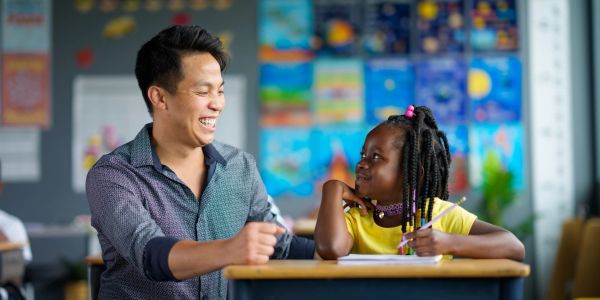 Dedicated teacher guiding a student with a smile in the classroom.