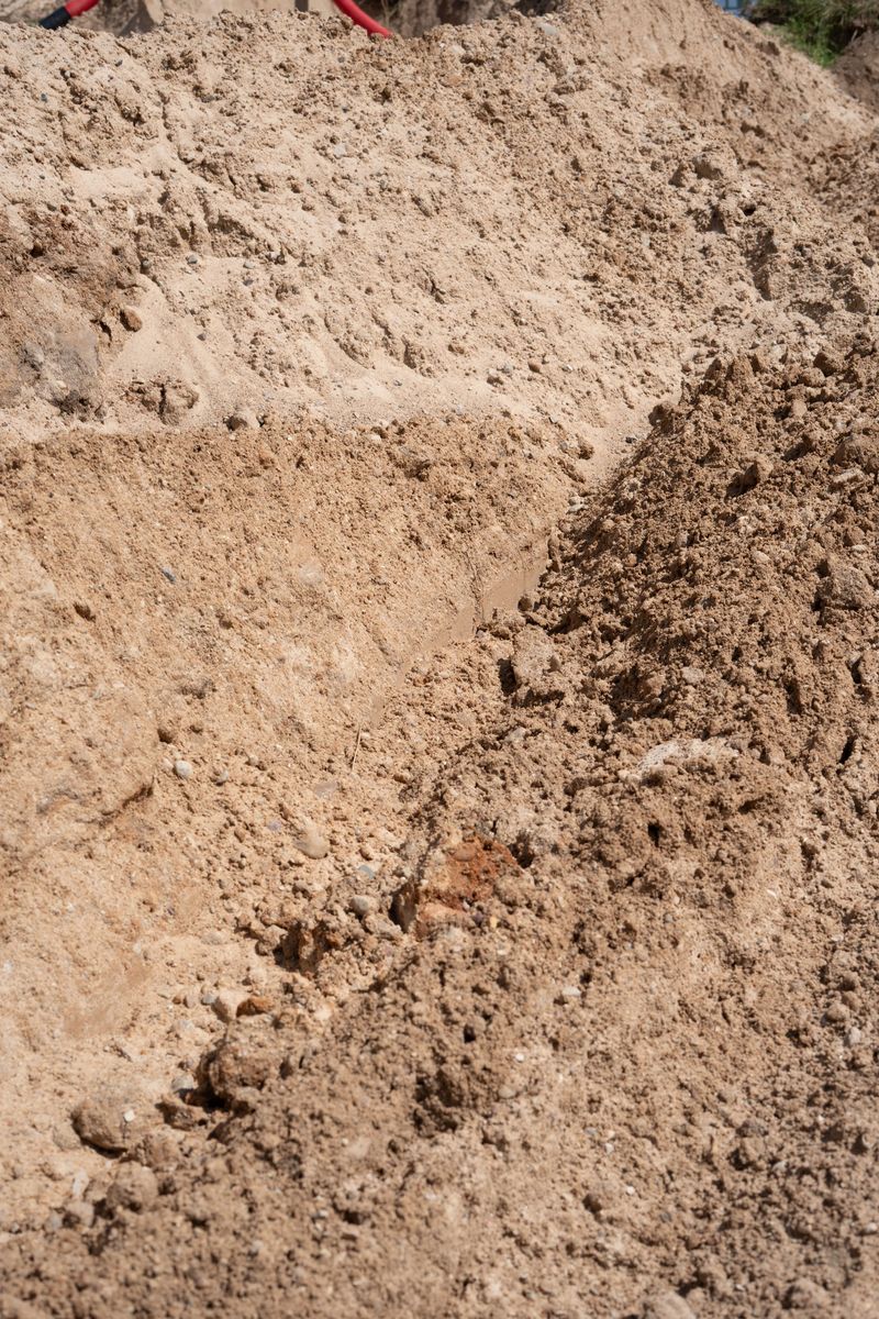 close-up view of excavated earth in construction site, featuring uneven terrain and distinct soil textures under bright natural sunlight, dig, process, trench, daytime, exposing, field, section