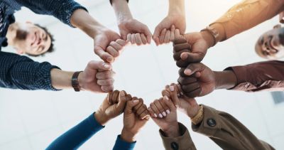Diverse group joining fists in unity from a low angle.