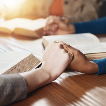 Two people holding hands over open books.