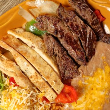 Grilled steak with tortillas, beans, cheese, and vegetables on a plate.