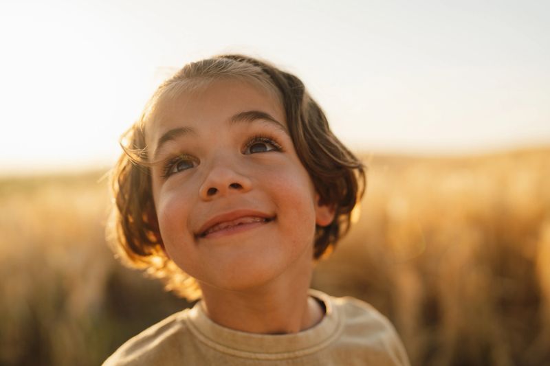 Photo of a cheerful young boy, posing for a portrait outdoors on the meadow