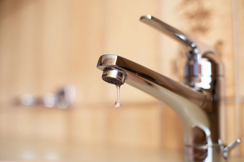 Dripping tap with inside apartment bathroom. Close up shot, shallow depth of field, no people