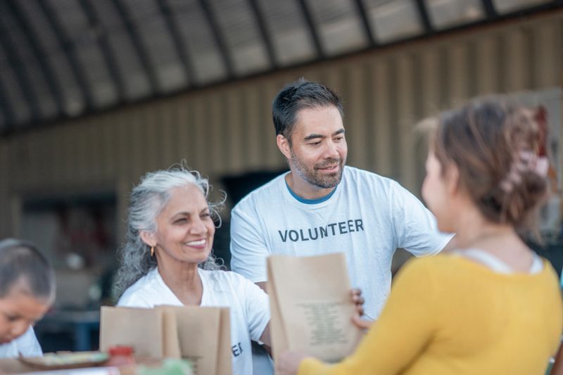 A group of cheerful volunteers work together in distributing food bags to community members in need, fostering a sense of unity, generosity, and care.