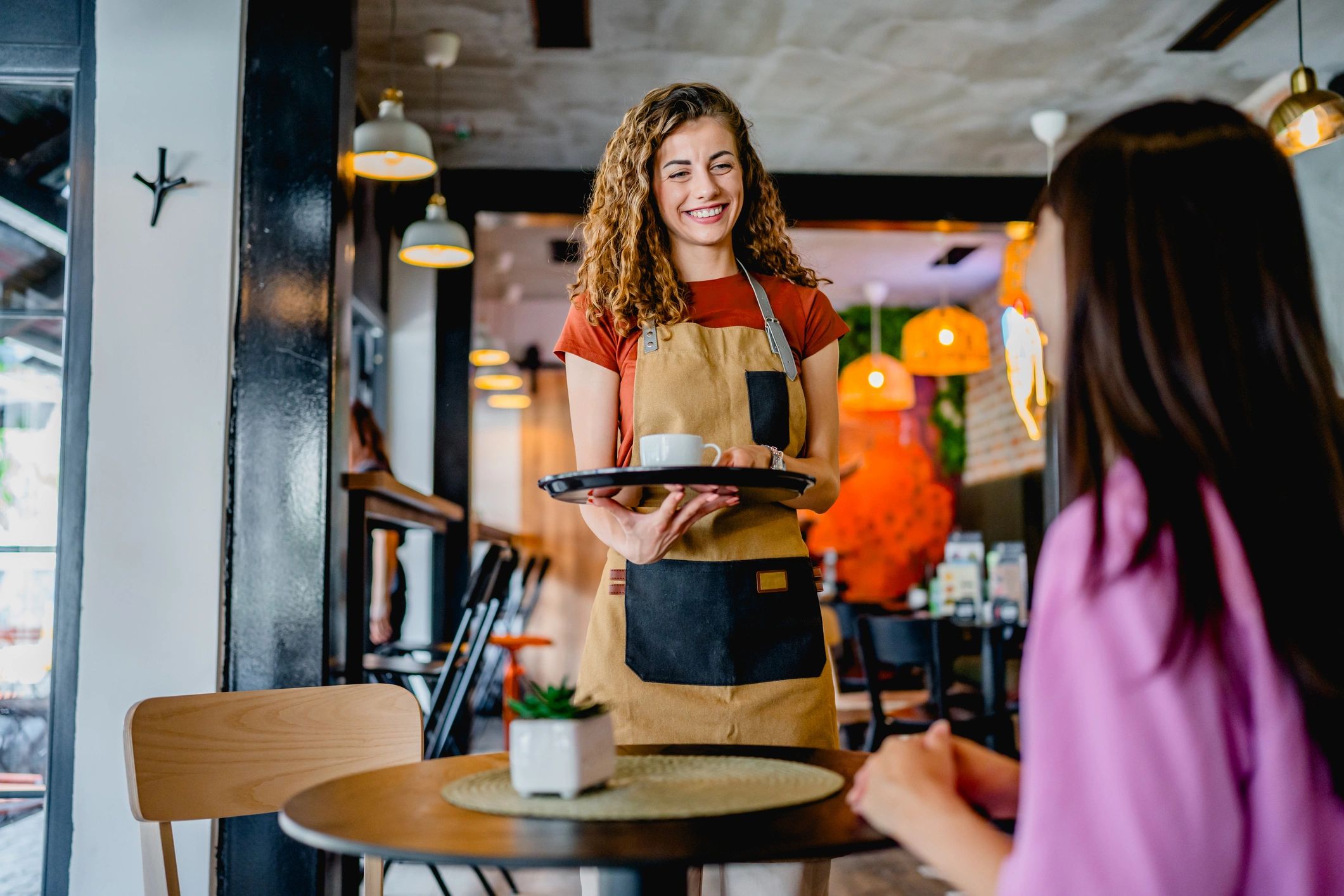Smiling waitress serving coffee in a cozy café.