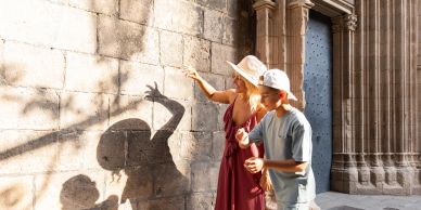 Two people play with shadows on a stone wall.